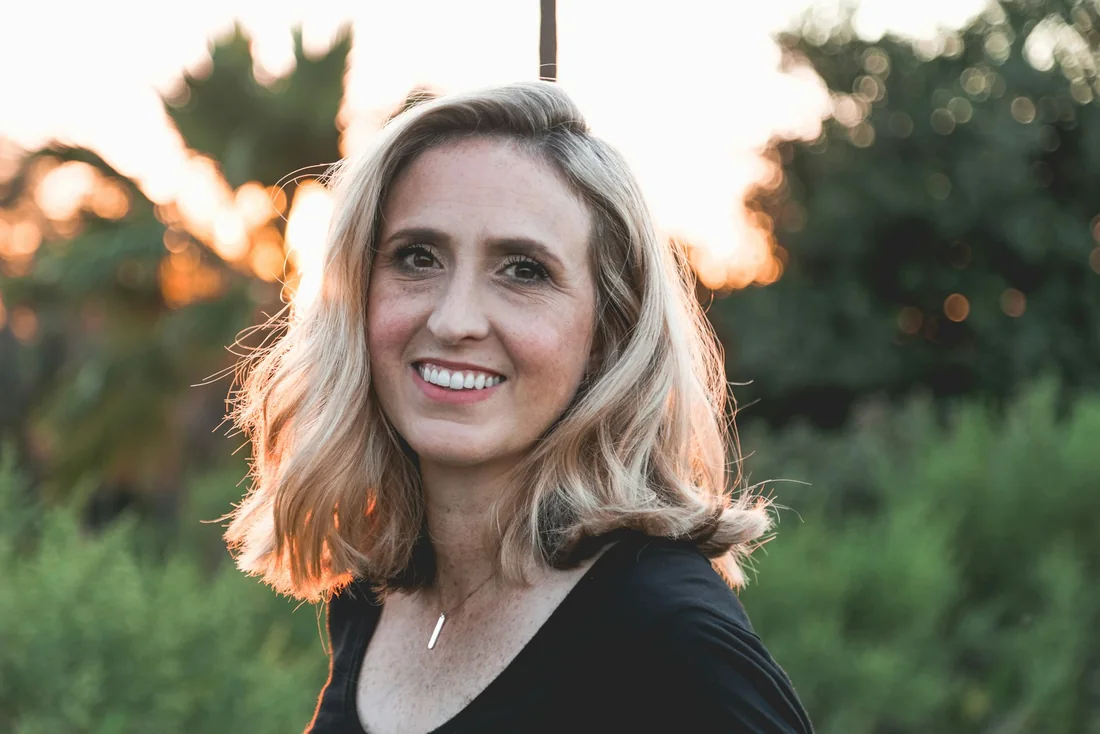 Mulher sorrindo em ambiente externo, representando atendimento próximo
